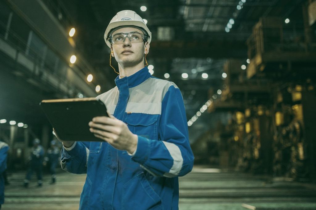 Technician with hard hat and tablet in an industrial plant